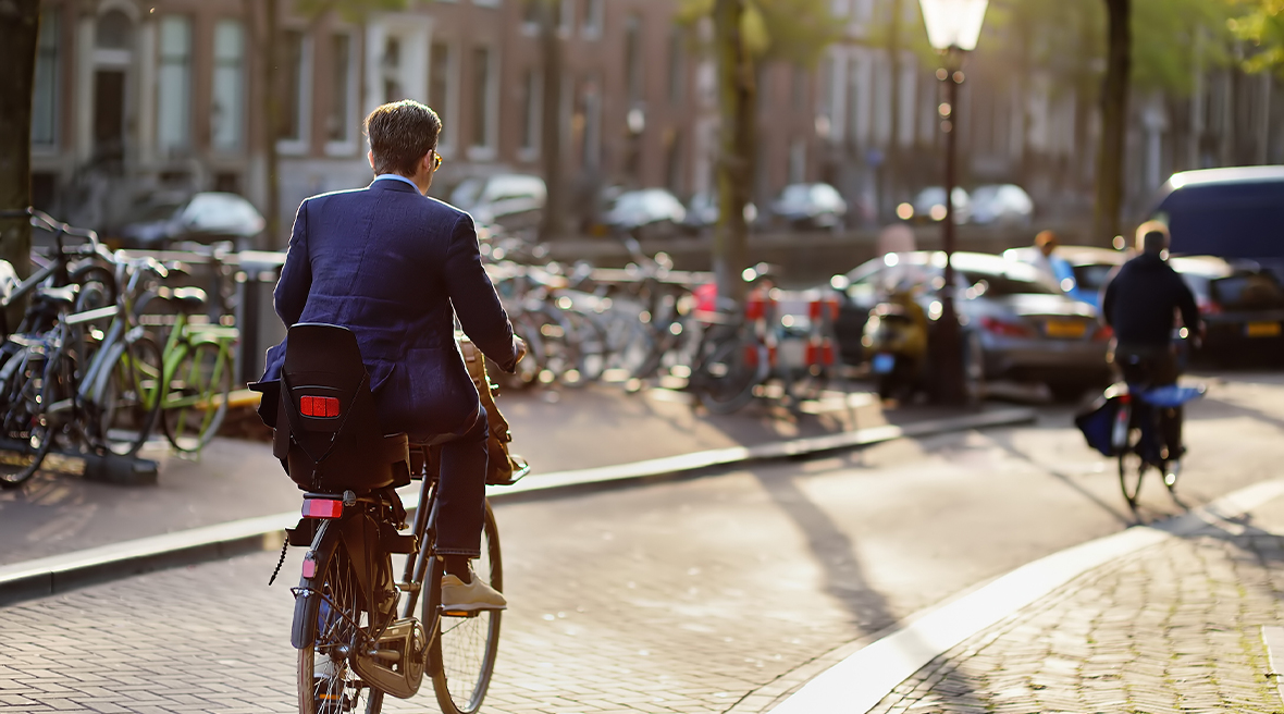 Man in a suit riding a bicycle in historical town of Amsterdam